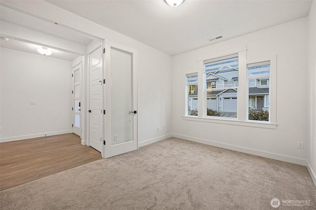 carpeted empty room with visible vents and baseboards