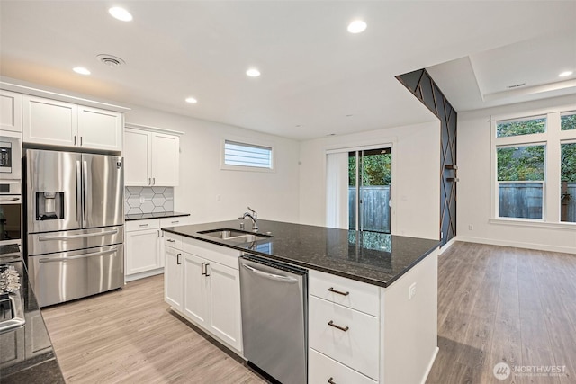 kitchen with light wood finished floors, appliances with stainless steel finishes, a sink, and a wealth of natural light