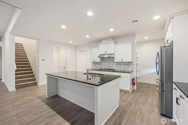 kitchen featuring visible vents, light wood-style floors, appliances with stainless steel finishes, under cabinet range hood, and backsplash