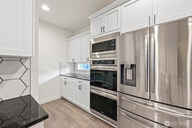 kitchen featuring light wood-style floors, white cabinetry, stainless steel appliances, and decorative backsplash