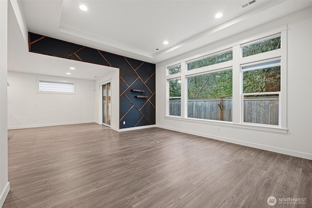 unfurnished living room with a raised ceiling, baseboards, and wood finished floors