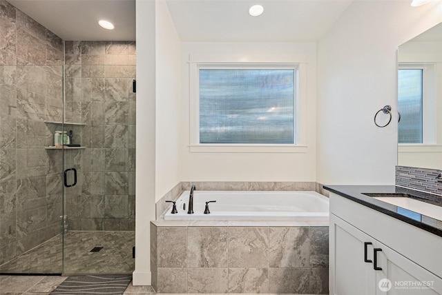 full bath with a healthy amount of sunlight, a garden tub, vanity, and a stall shower