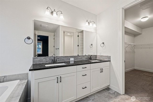 full bathroom with a spacious closet, double vanity, a tub to relax in, and a sink