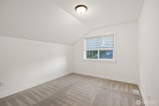 additional living space featuring carpet floors, lofted ceiling, visible vents, and baseboards