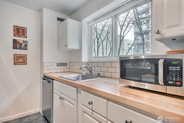 kitchen with a sink, stainless steel appliances, visible vents, and white cabinetry