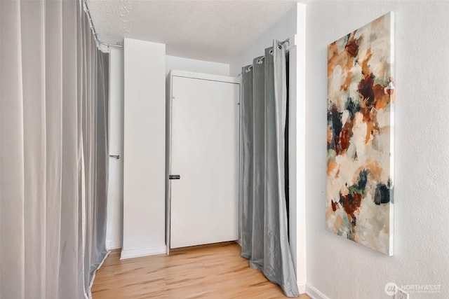 hall featuring light wood finished floors and a textured ceiling