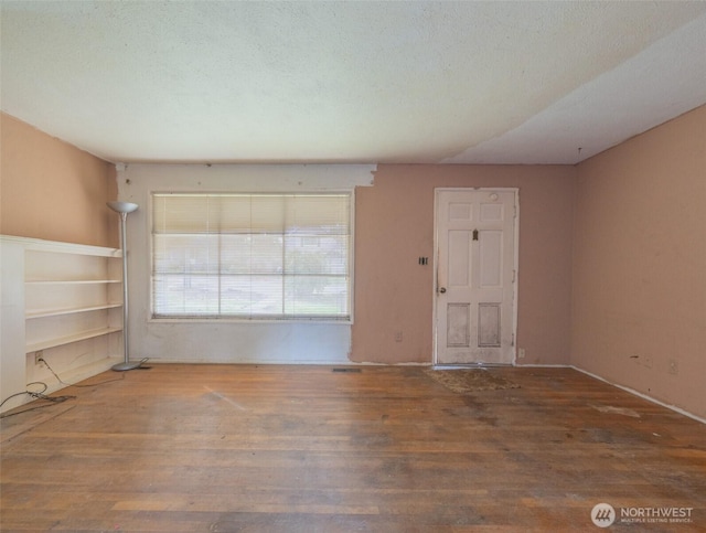 empty room featuring a textured ceiling and wood finished floors