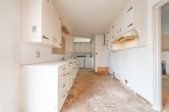 kitchen with independent washer and dryer, light countertops, concrete floors, and a sink