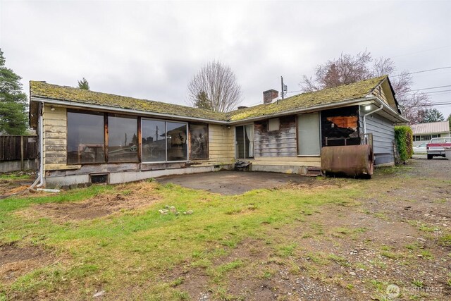 back of property featuring a patio area, a chimney, and a sunroom