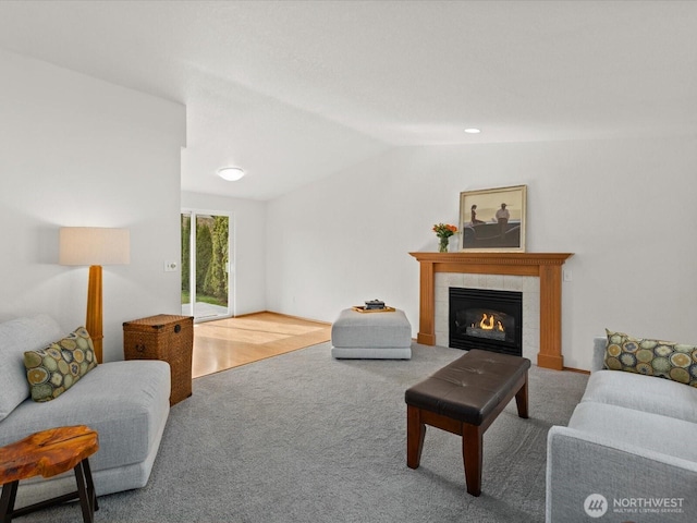 carpeted living area featuring a tile fireplace and vaulted ceiling