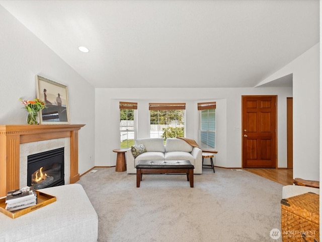 living area with carpet flooring, lofted ceiling, baseboards, and a fireplace