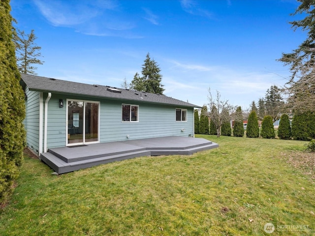 rear view of house featuring a deck and a lawn