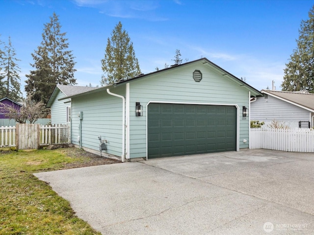 garage featuring driveway and fence