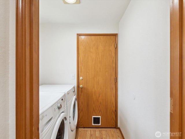 laundry room featuring laundry area, light wood-type flooring, and washing machine and clothes dryer