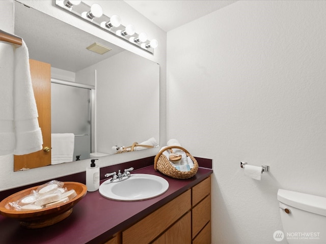 full bath with visible vents, a stall shower, toilet, and vanity