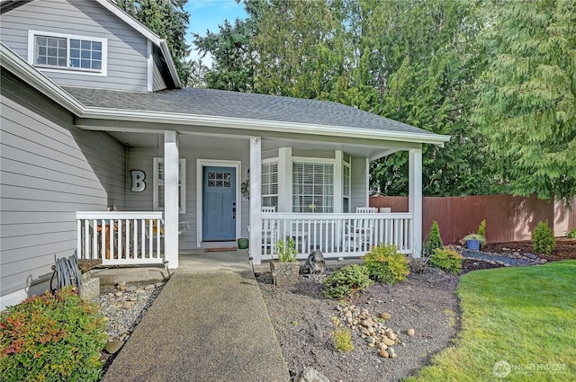 property entrance with covered porch, a lawn, roof with shingles, and fence