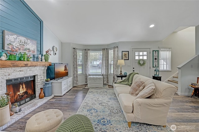 living area featuring stairway, a brick fireplace, baseboards, and wood finished floors