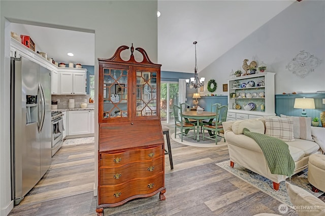 kitchen featuring light wood finished floors, appliances with stainless steel finishes, white cabinets, and an inviting chandelier