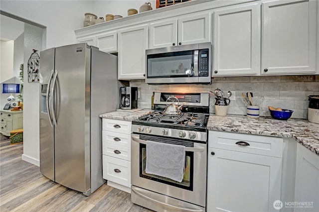 kitchen featuring white cabinetry, light wood-style flooring, tasteful backsplash, and appliances with stainless steel finishes