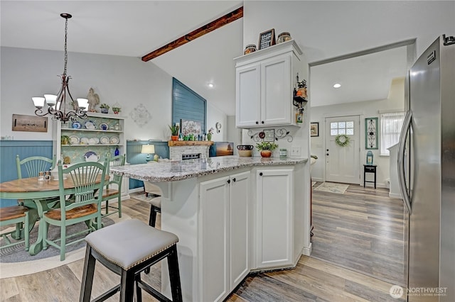 kitchen with a peninsula, white cabinets, light wood-style flooring, and freestanding refrigerator