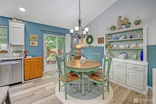 dining area with light wood finished floors, a chandelier, and vaulted ceiling