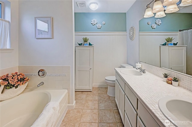 bathroom featuring double vanity, visible vents, a wainscoted wall, and a sink