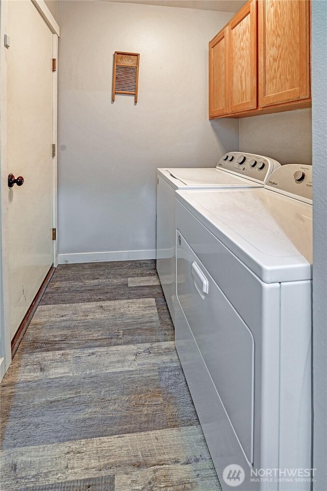 laundry area featuring washer and dryer, baseboards, cabinet space, and dark wood-style floors