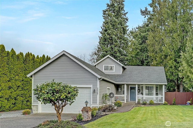 traditional home featuring a front lawn, a porch, fence, a shingled roof, and a garage