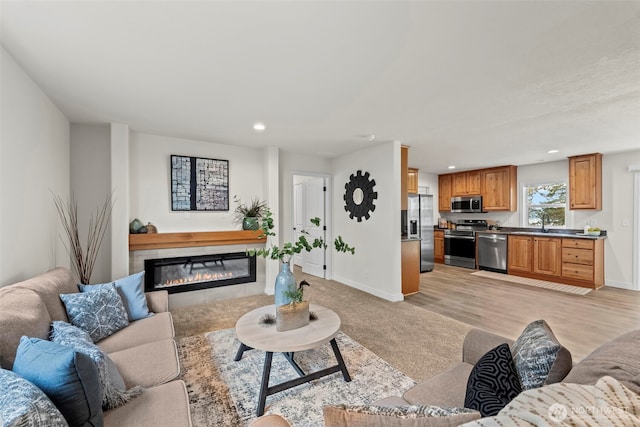 living room with recessed lighting, a tile fireplace, light wood-type flooring, and baseboards