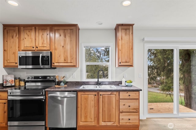 kitchen featuring a sink, stainless steel appliances, dark countertops, and recessed lighting