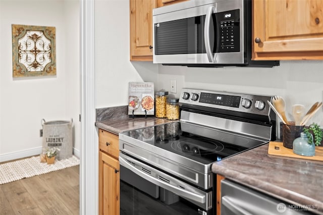 kitchen featuring stainless steel appliances, baseboards, and wood finished floors