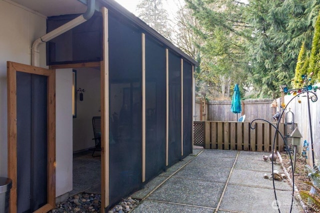 view of outbuilding with fence and a sunroom