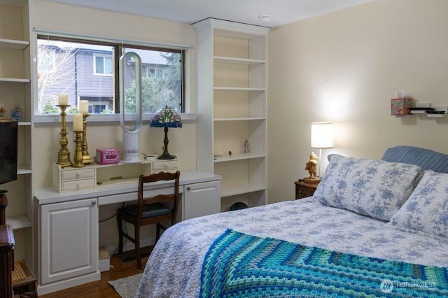 bedroom with dark wood finished floors and built in study area