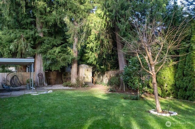 view of yard featuring a shed, an outdoor structure, and fence