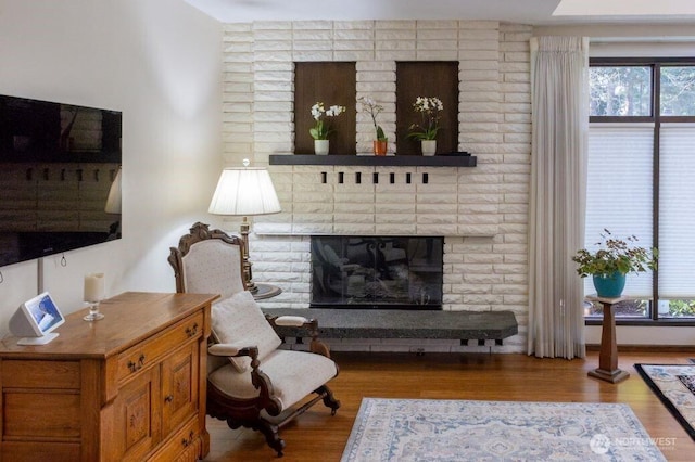 living room with a wealth of natural light, a brick fireplace, and wood finished floors