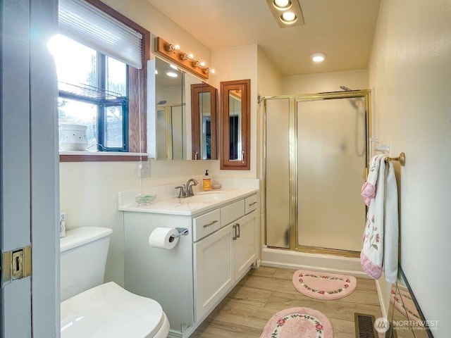 bathroom with a stall shower, toilet, and vanity