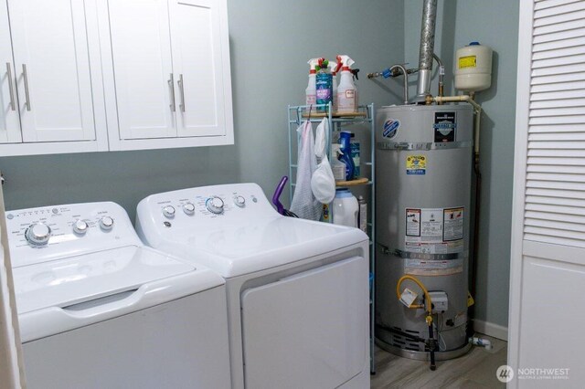 laundry room featuring strapped water heater, cabinet space, wood finished floors, and separate washer and dryer