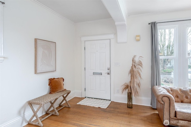 foyer featuring baseboards, ornamental molding, and light wood finished floors