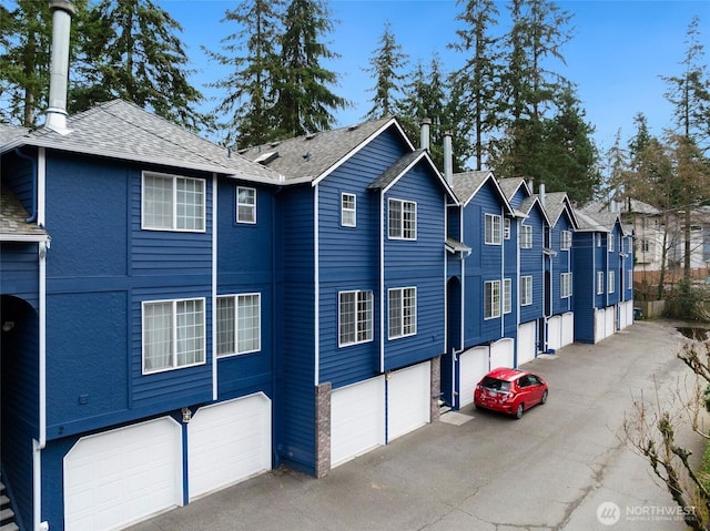 view of front of home with a garage, a residential view, roof with shingles, and aphalt driveway