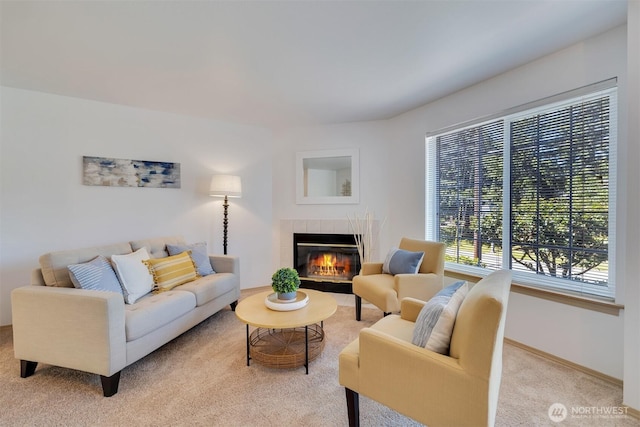 living room featuring a tile fireplace, baseboards, and carpet