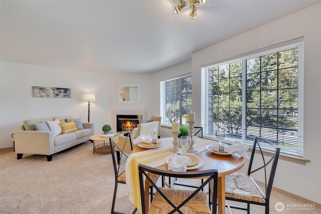 dining space featuring light carpet and a tile fireplace