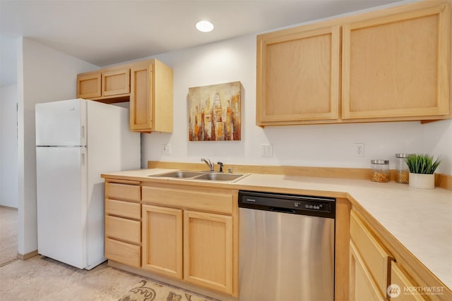 kitchen featuring light brown cabinets, light countertops, stainless steel dishwasher, freestanding refrigerator, and a sink