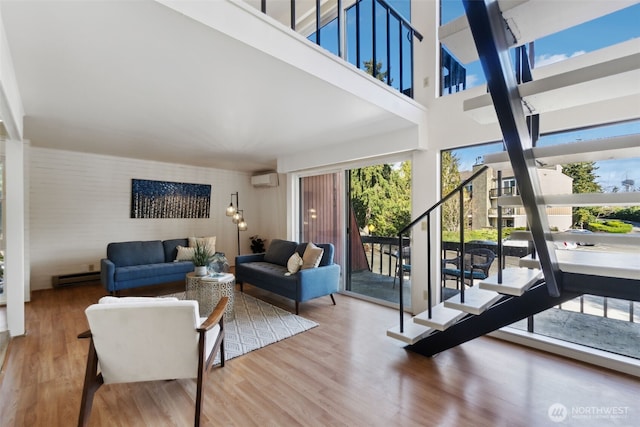 living room with a baseboard radiator, wood finished floors, stairs, and a wall mounted AC