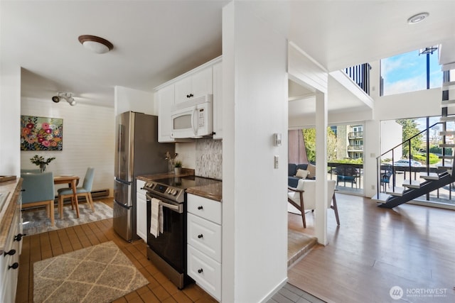 kitchen featuring white microwave, tasteful backsplash, stainless steel range with electric stovetop, dark wood-style floors, and white cabinets