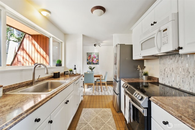 kitchen with electric range, a sink, light tile patterned flooring, white cabinets, and white microwave