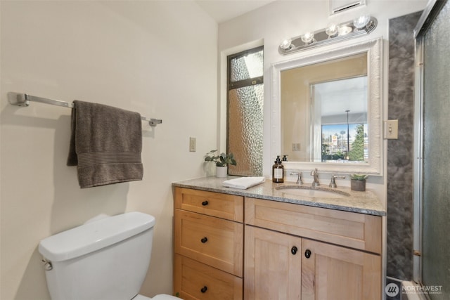 bathroom featuring a shower with door, toilet, and vanity