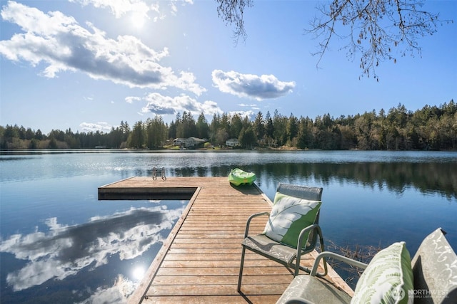 view of dock with a water view and a forest view