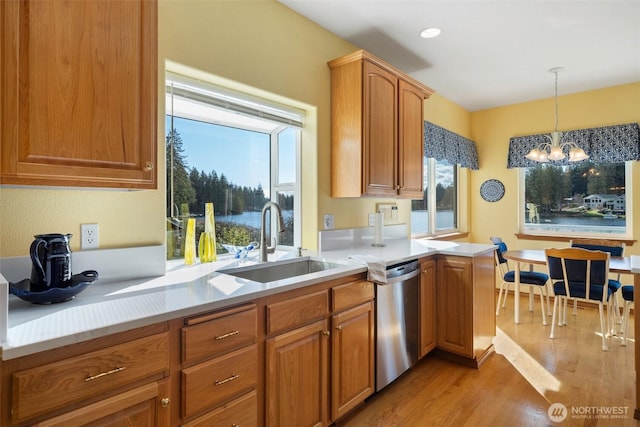 kitchen featuring light countertops, a sink, light wood finished floors, and stainless steel dishwasher