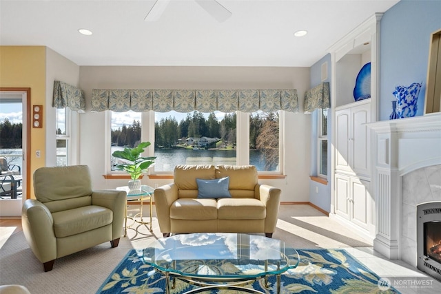 sunroom with ceiling fan, a tiled fireplace, a water view, and heating unit