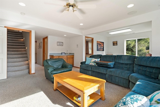 living area featuring stairs, light colored carpet, a ceiling fan, and recessed lighting